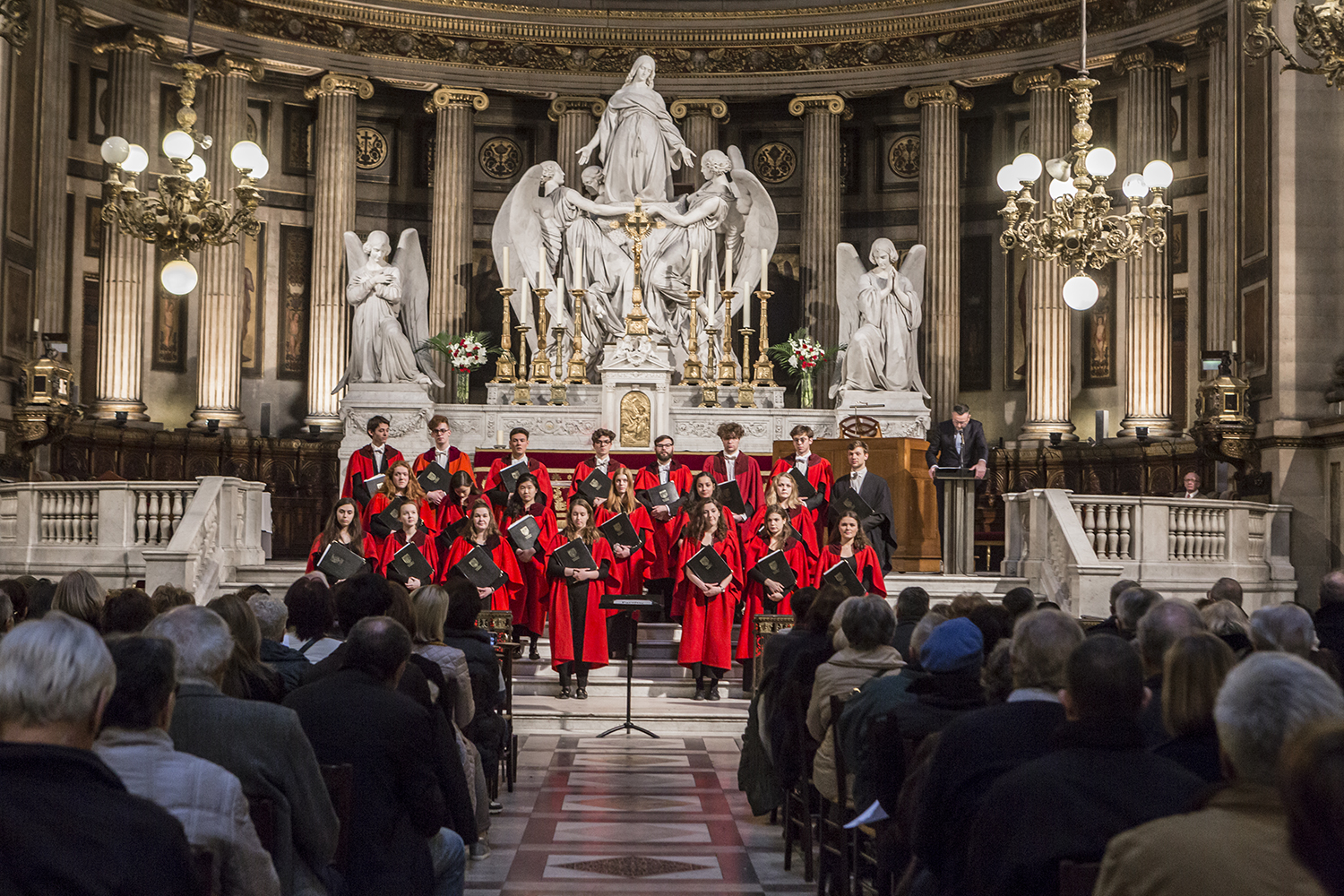 Choir in red cassocks performing in La Madeleine Paris, full house