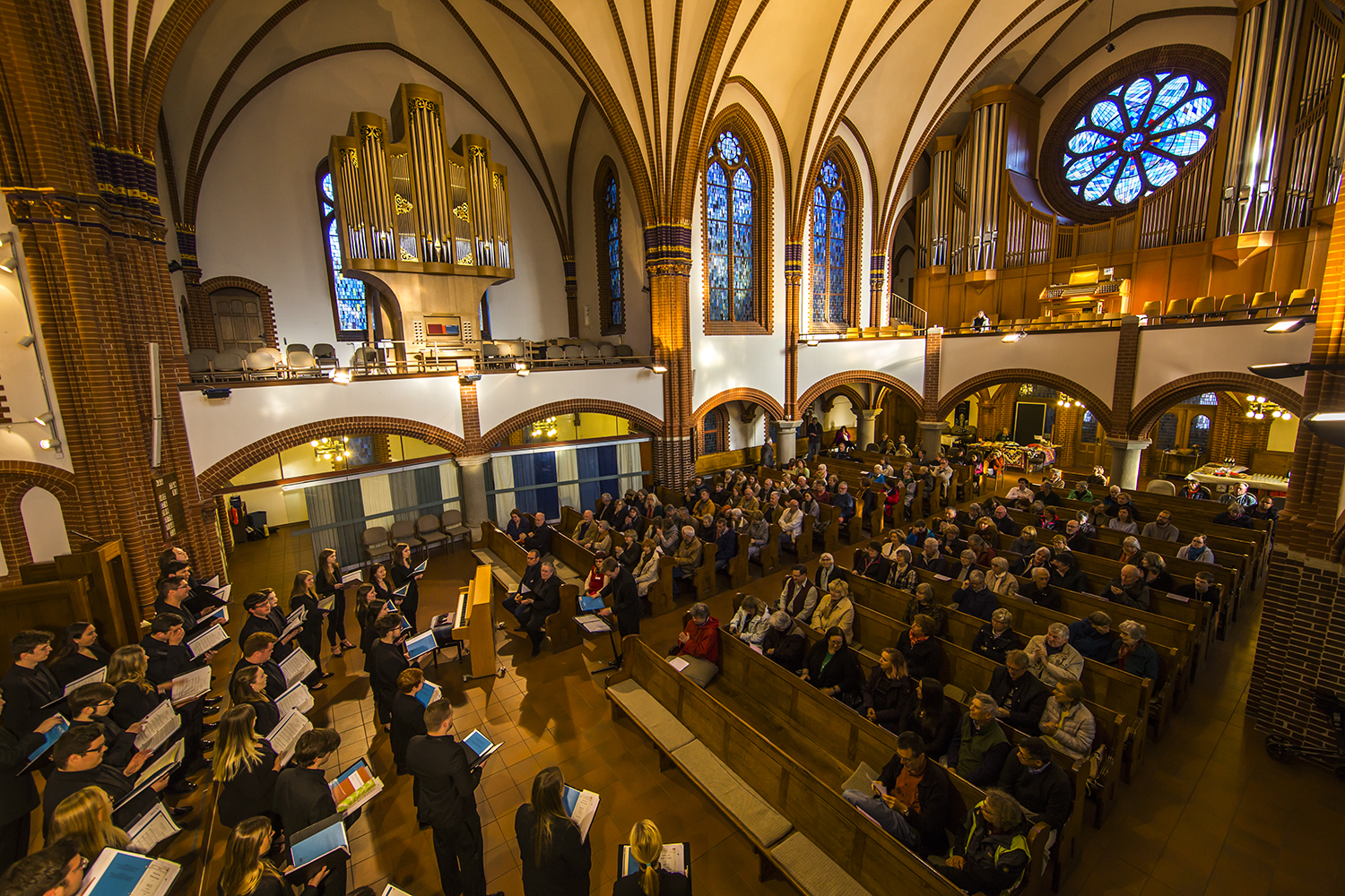 Panoramic photo of choir performing to an audience in a church