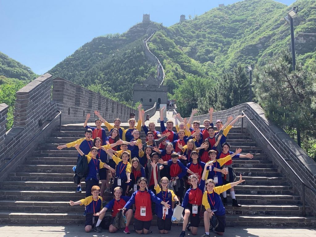 Group post on great wall of china steps, arms extended