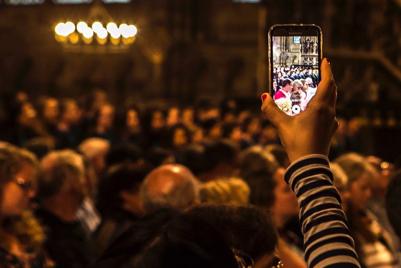 An audience member filming a concert through their smartphone